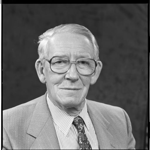 Black and white head and shoulders photograph of Gordon Wilson, a former Member of Seanad Éireann, standing in a garden.